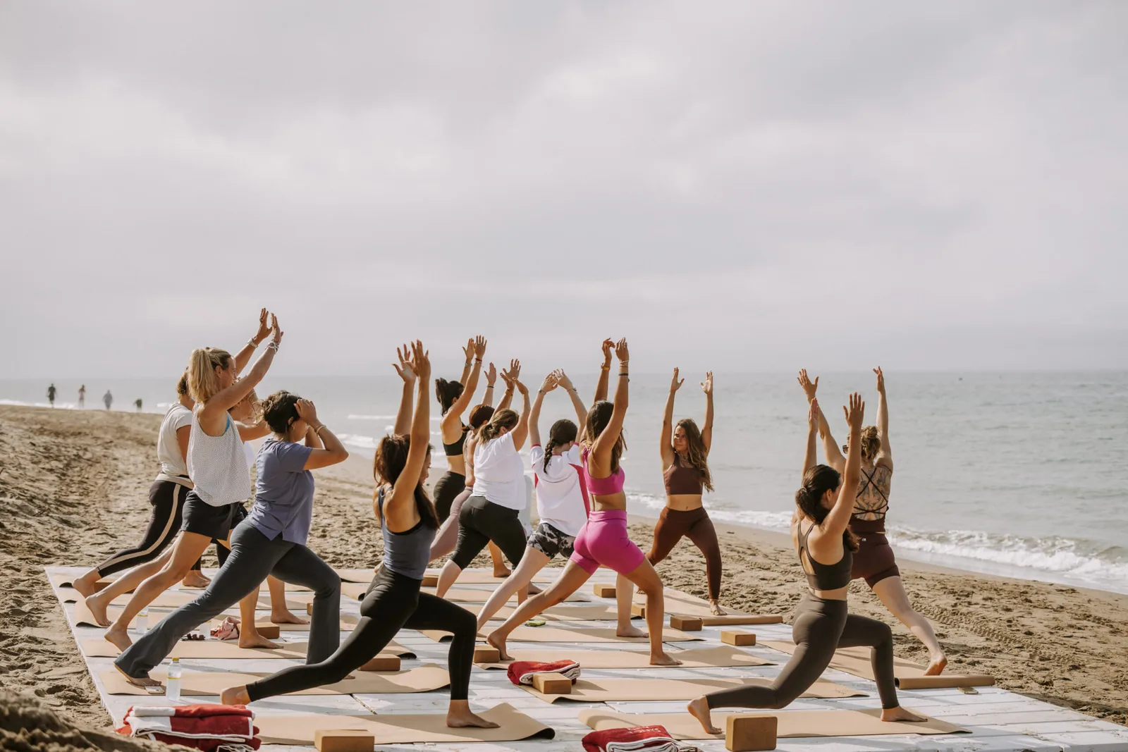 Alumna de yoga en zancada alta durante una clase en la playa de Marbella